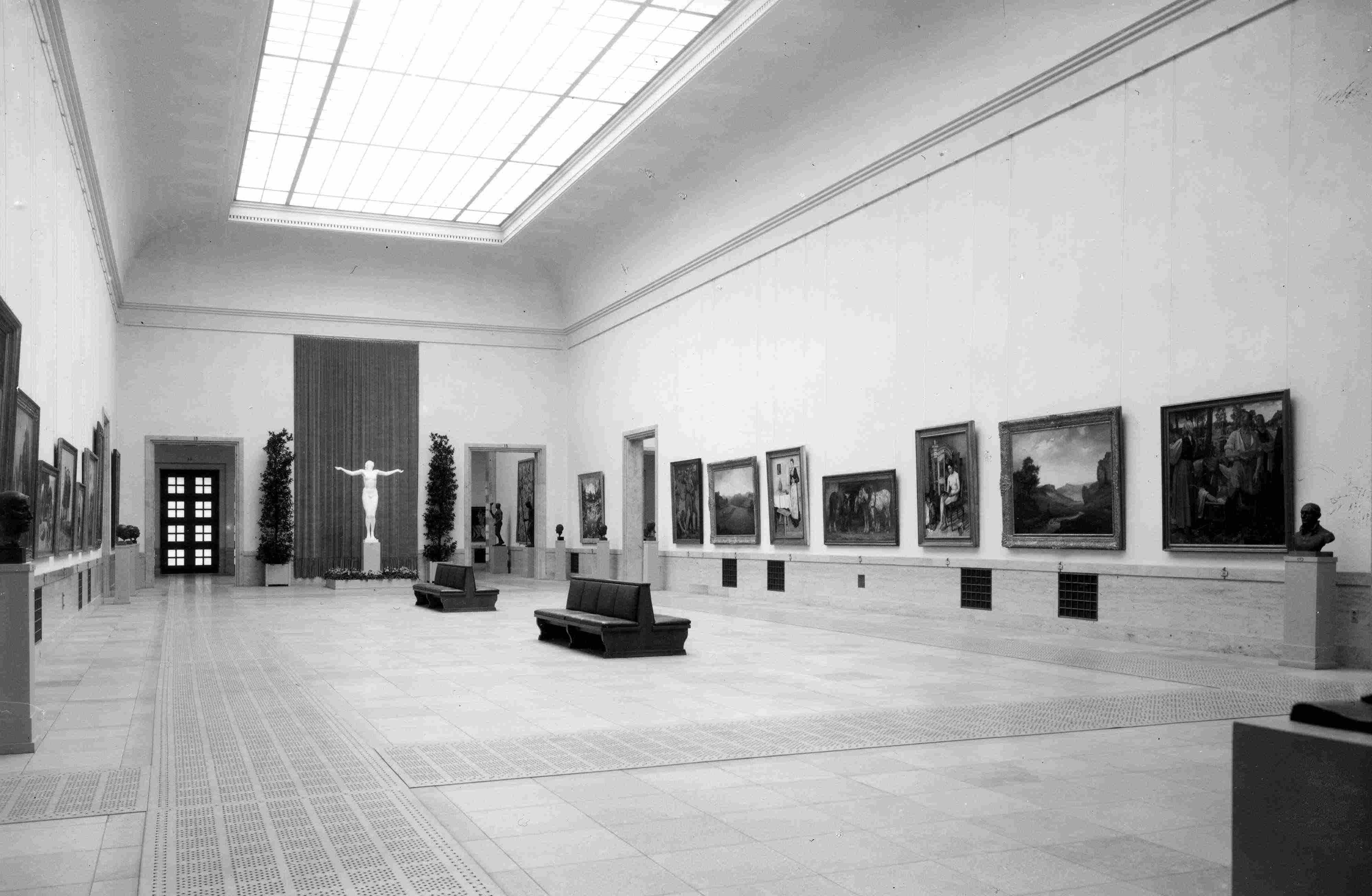 Large museum hall with paintings, sculptures and busts on the walls. 