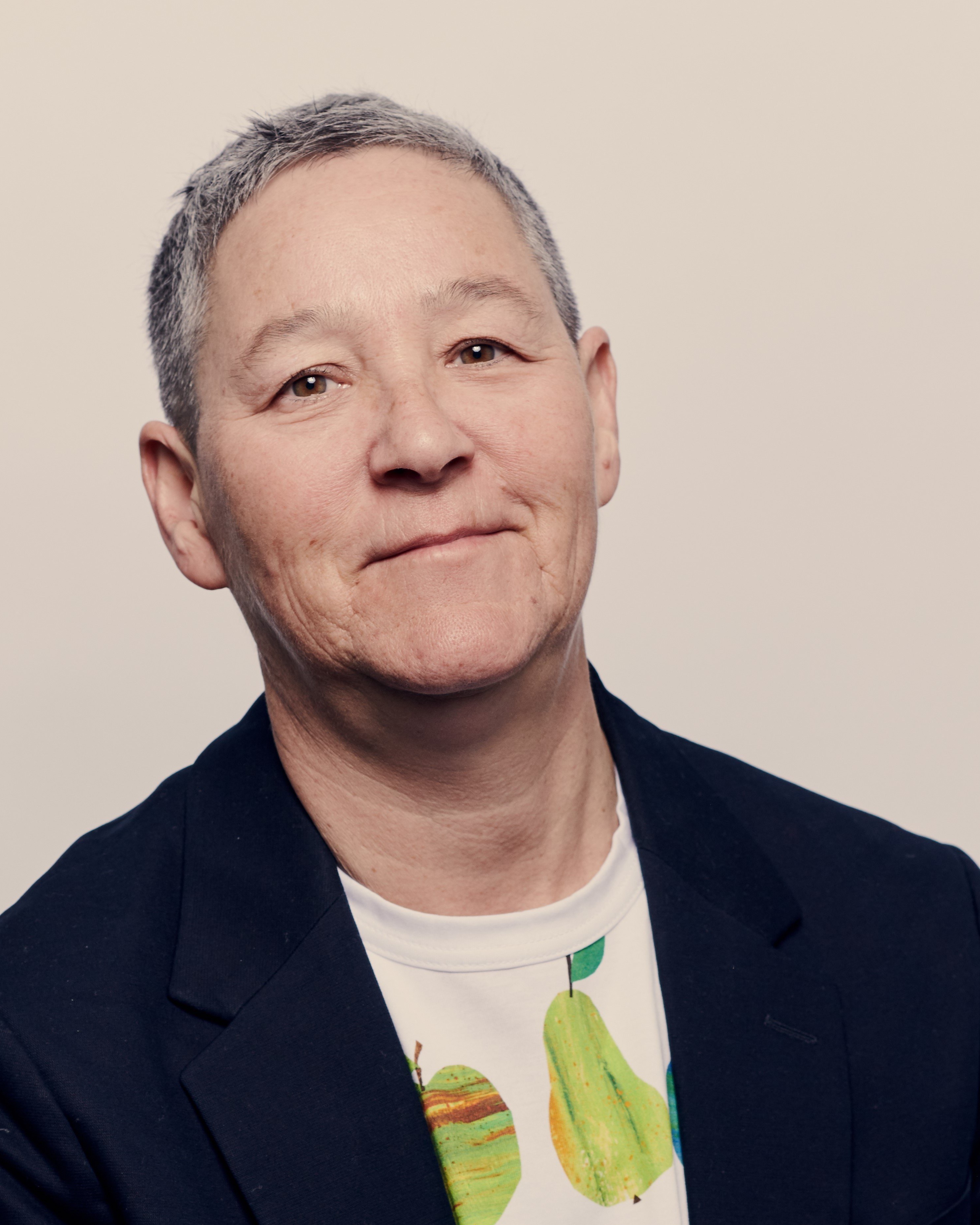 A man with short gray hair. He is wearing a black jacket and a white shirt.