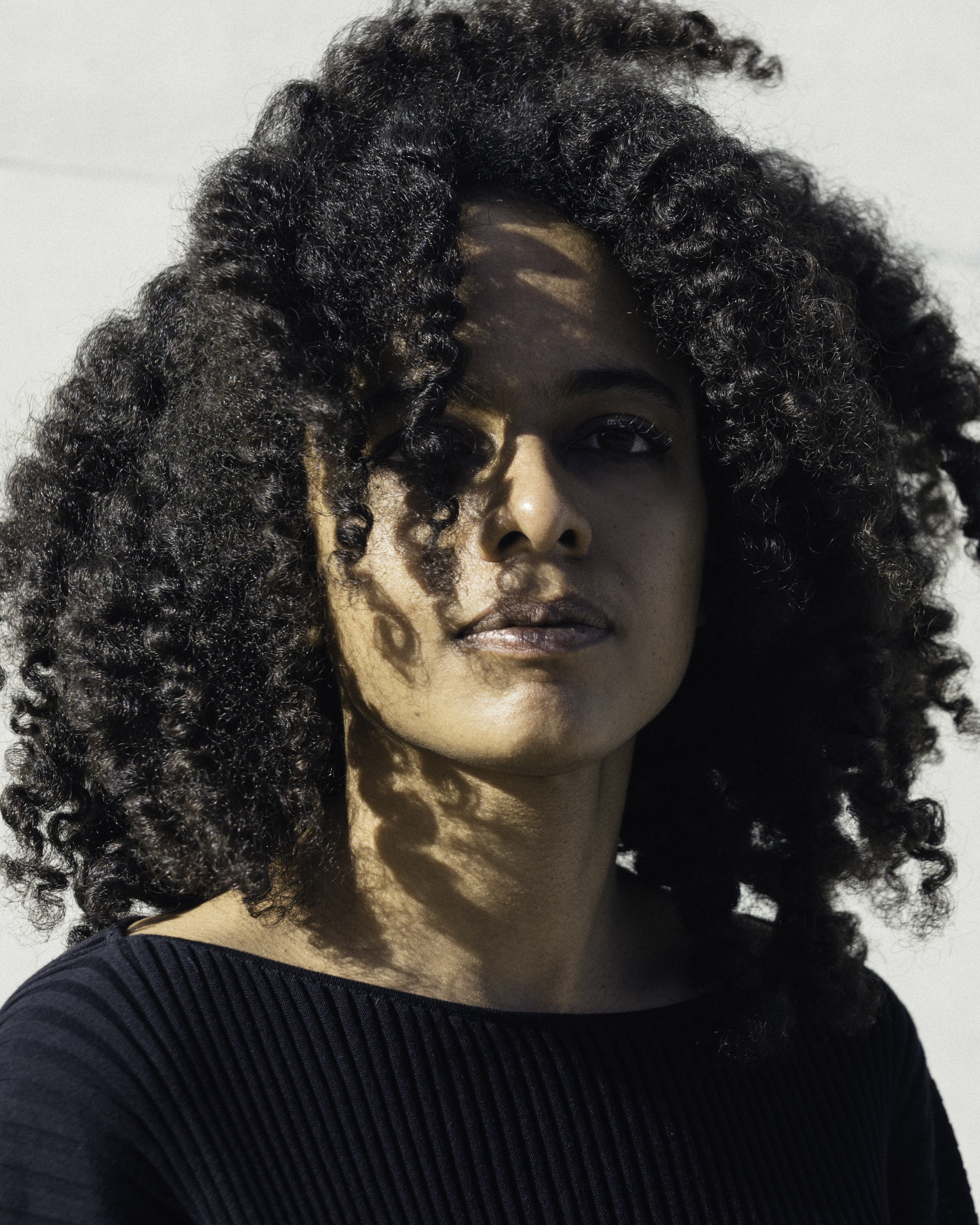 A woman with a black Afro. She is wearing a black top.