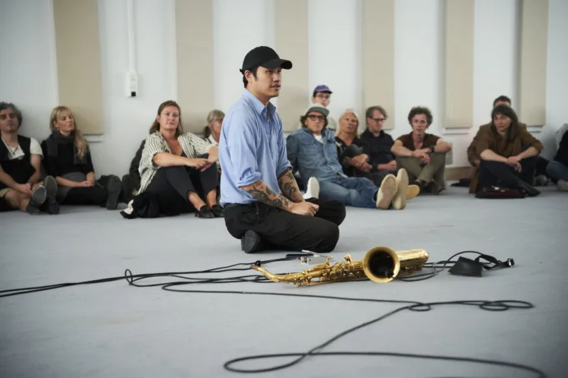 Ein Musiker und ein Instrument in Mitten von Menschen. Künstlergespräch.