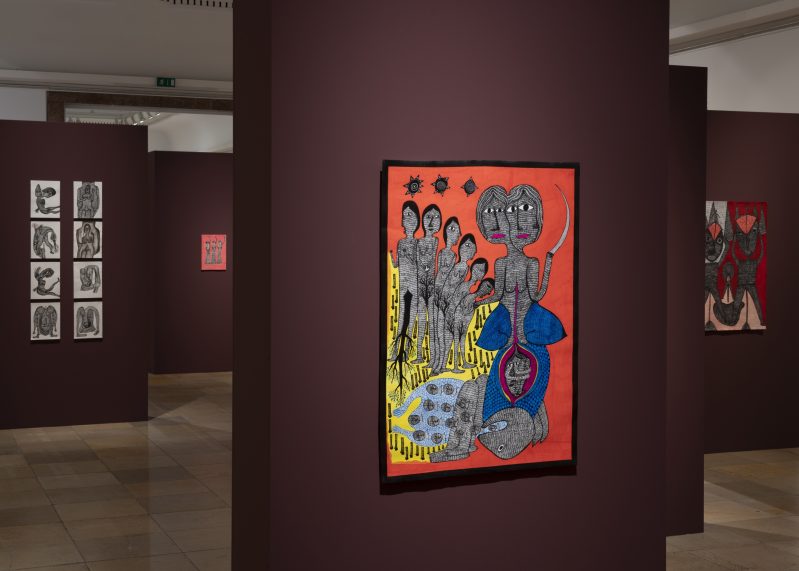 Ausstellungsansicht mit Gemälden, die an roten Wänden hängen.