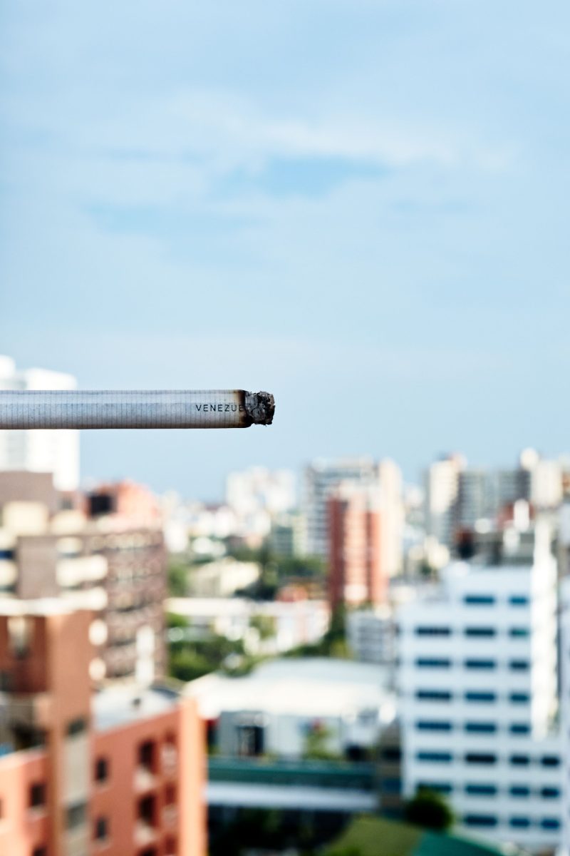 Eine Nahaufnahme einer brennenden Zigarette vor dem Hintergrund einer Stadt.
