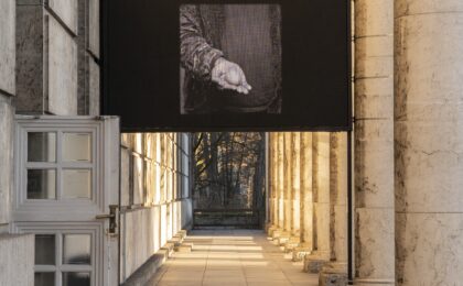 Ein Bildschirm mit Videofilm zwischen Säulen auf der Terrasse.