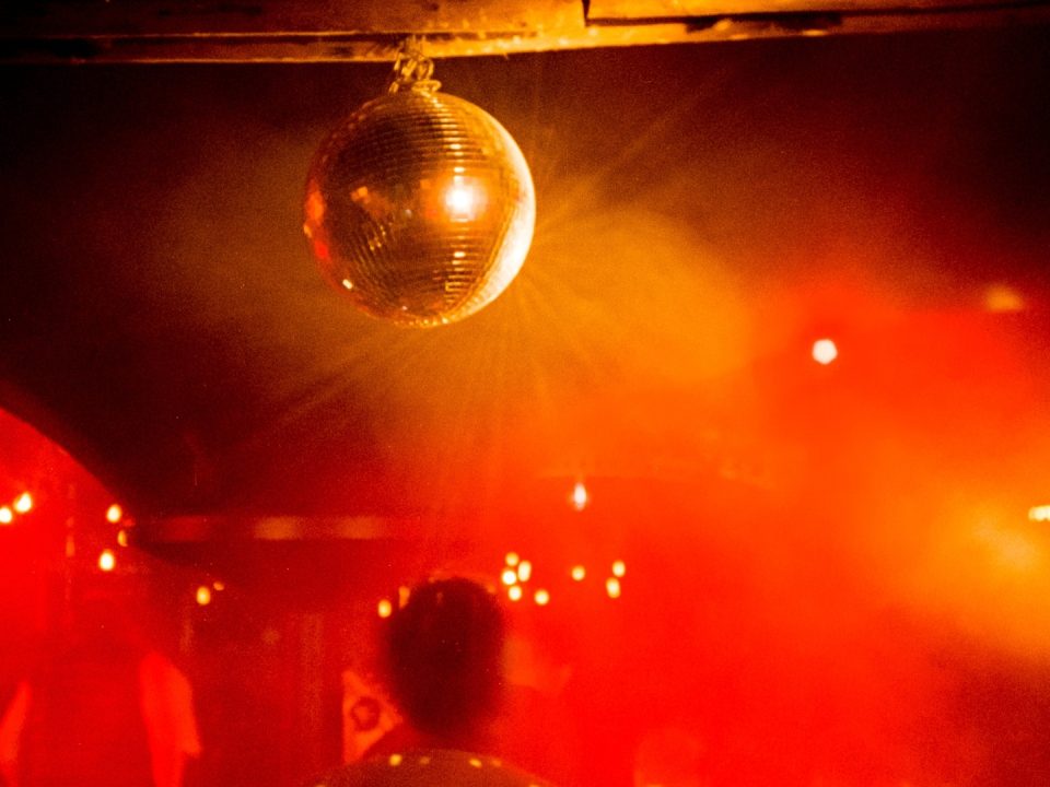 Eine rot beleuchtete Tanzfläche mit Disko-Kugel.